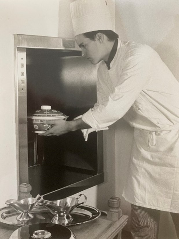 Old photograph of a chef using a dumbwaiter
